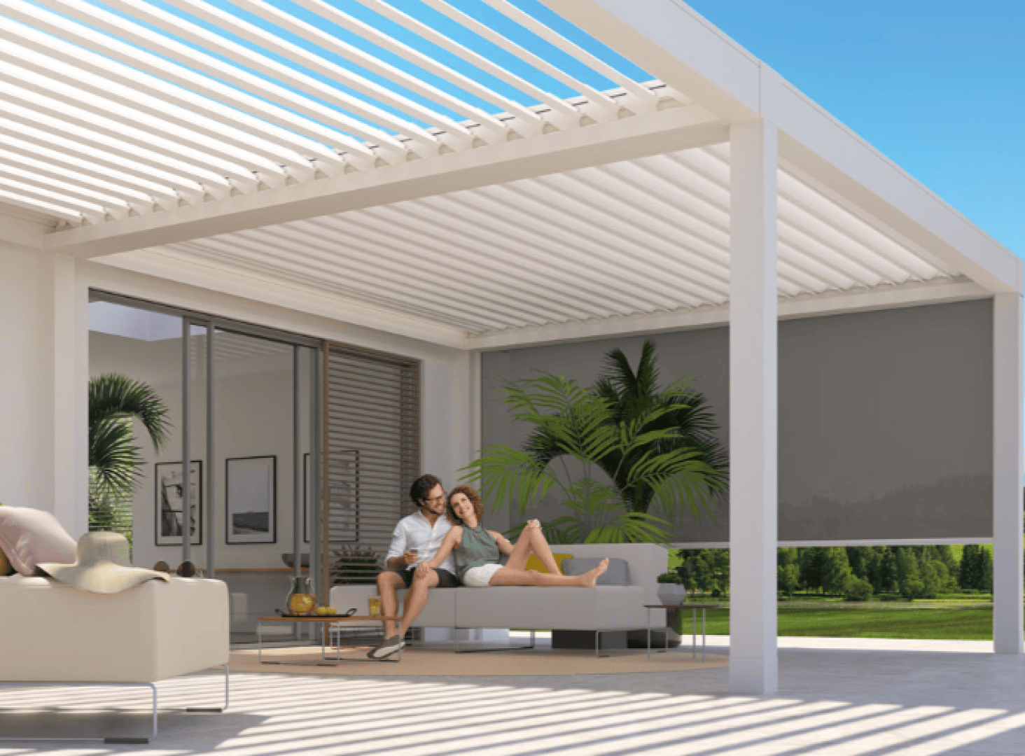 A couple relaxes on a sofa under a modern white pergola with a slatted roof in a stylish outdoor living space, surrounded by greenery and sunlight. Large windows and plants complete the serene setting.
