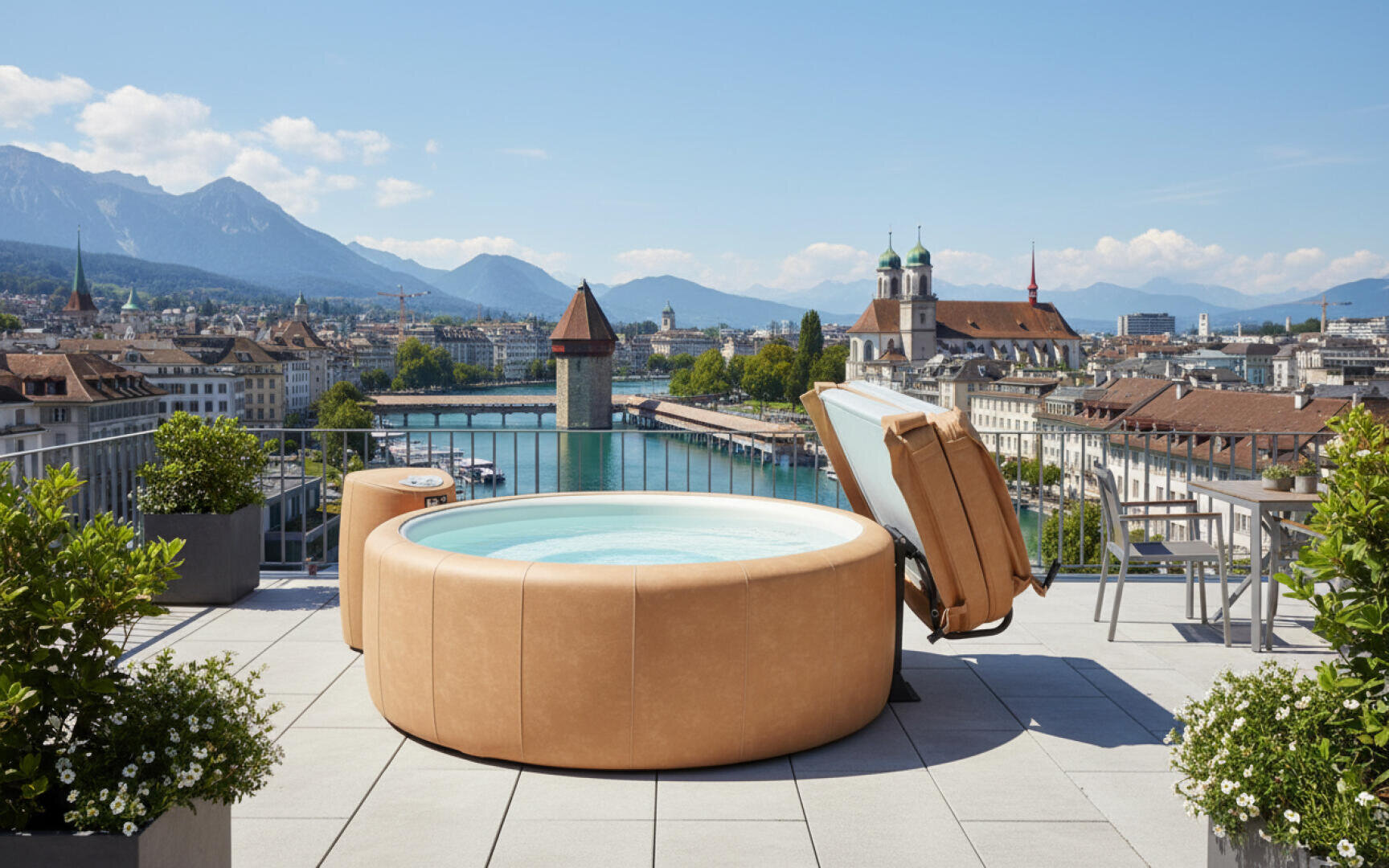 Eine Dachterrasse mit einem runden Whirlpool mit Blick auf eine malerische Stadtlandschaft, einen Fluss, einen historischen Turm, eine Kuppelkirche und Berge im Hintergrund unter einem klaren blauen Himmel. Topfpflanzen schmücken die Terrasse.