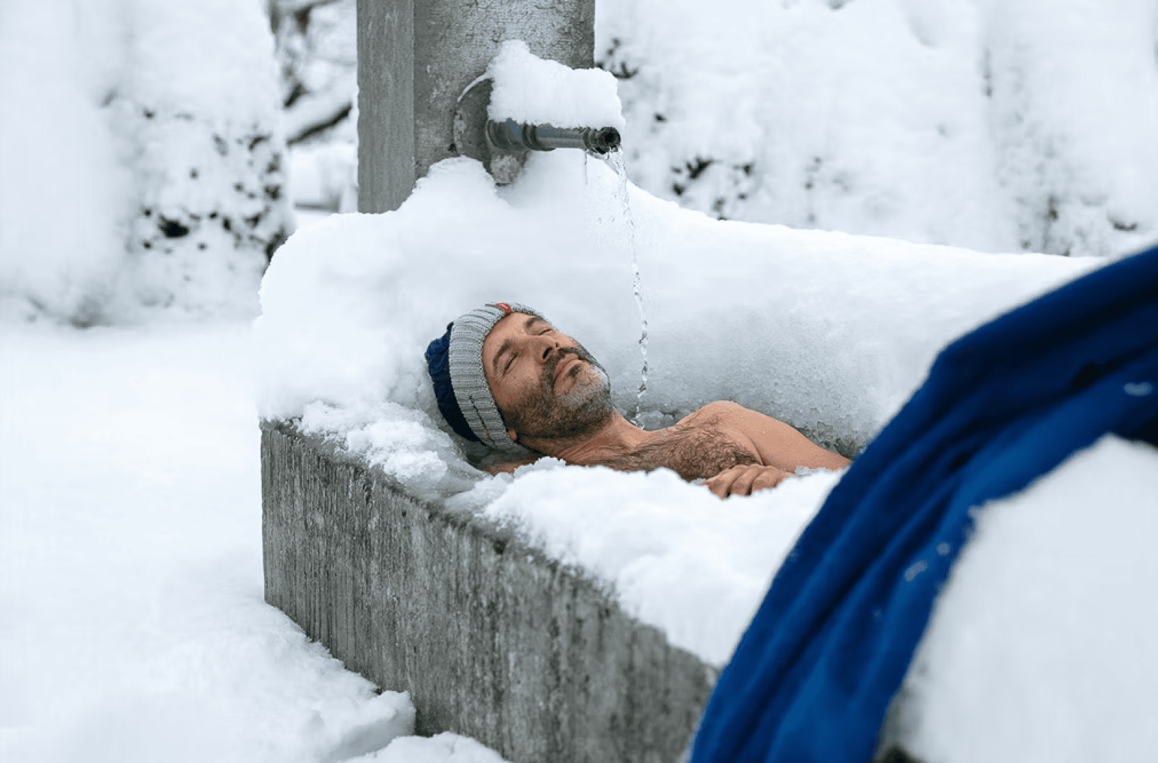 Ein Mann liegt in einer mit Schnee bedeckten Wanne.