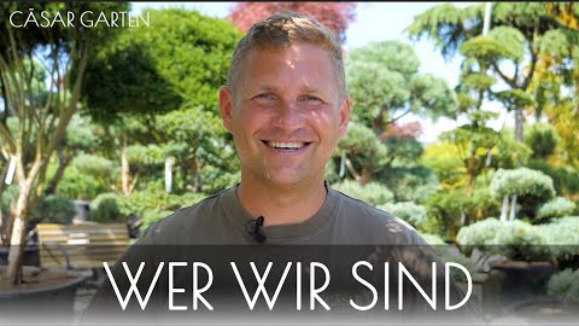 Ein lächelnder Mann steht im Freien in einem üppigen Garten mit verschiedenen grünen Bäumen. Oben links steht CÄSAR GARTEN, und unten steht in großer Schrift WER WIR SIND. Das Wetter scheint sonnig und angenehm zu sein.
