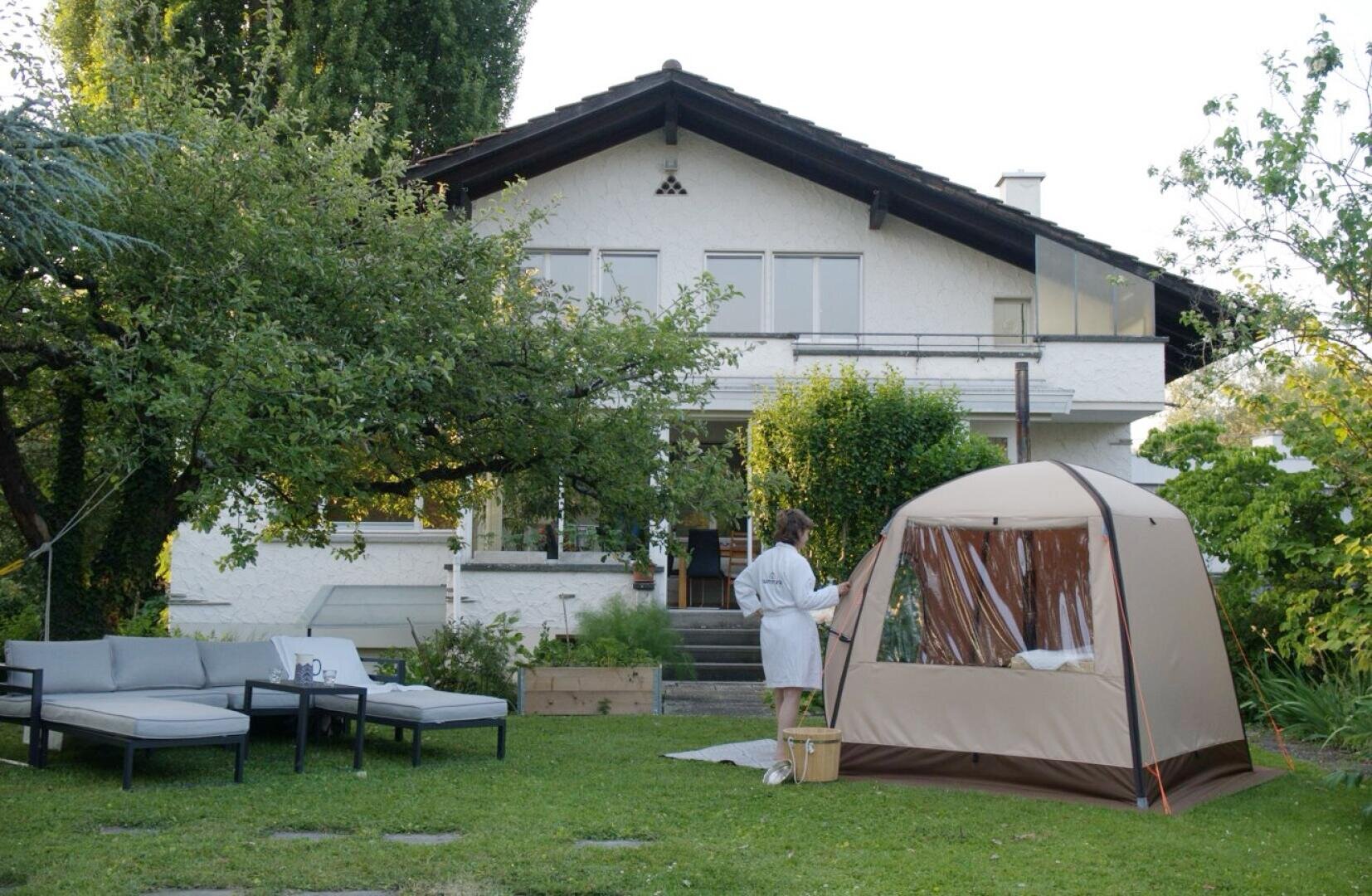 A woman stands in a courtyard next to a tent.