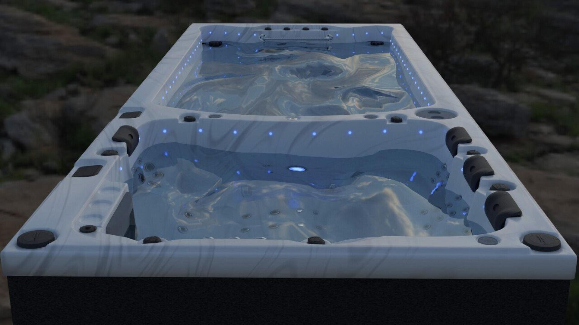 A modern outdoor hot tub with blue LED lights illuminating the water, surrounded by built-in seats and headrests, set against a natural rocky background.