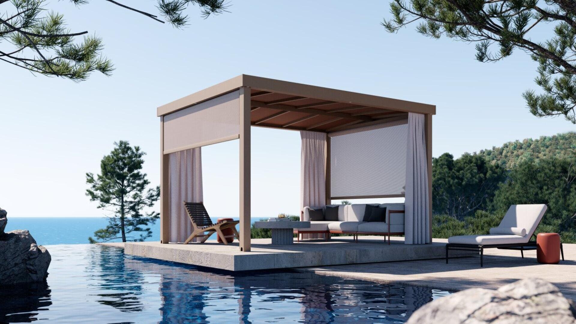 A modern outdoor cabana with curtains and lounge furniture sits beside a calm infinity pool, surrounded by trees and overlooking a scenic ocean view under a clear blue sky.