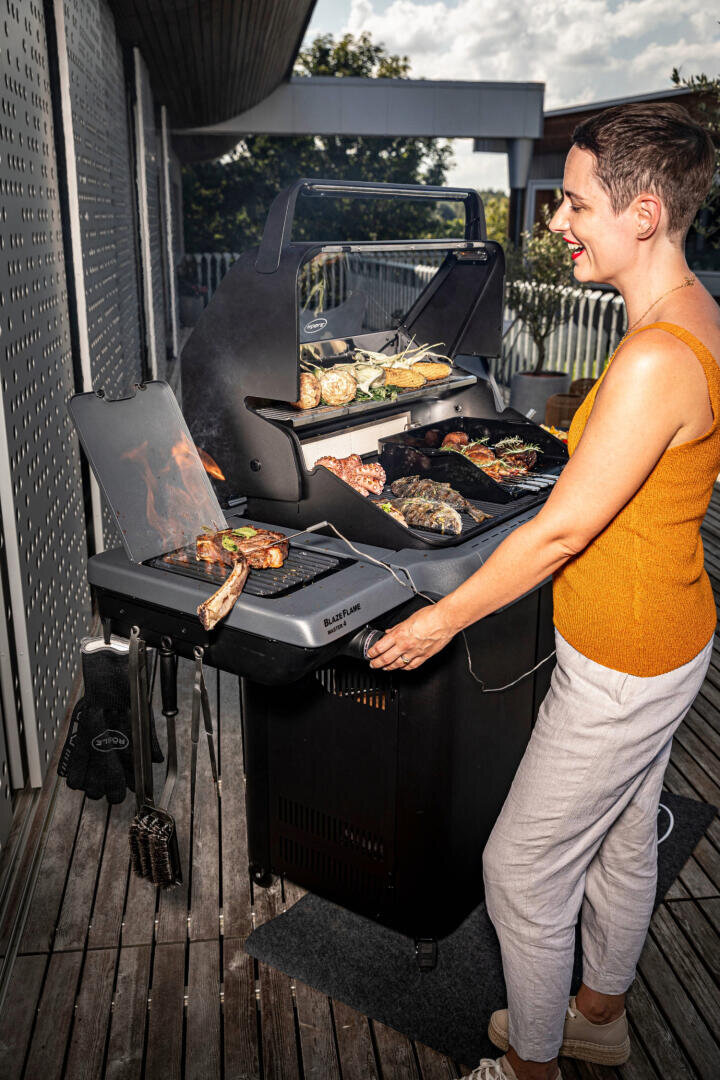 Eine Frau steht neben einem Grill.