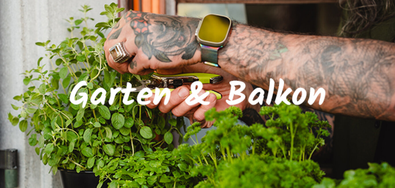 Tätowierte Hände, die Ringe und eine Smartwatch tragen, schneiden frische grüne Kräuter in einem Garten, wobei der Schriftzug Garten & Balkon über das Bild gelegt wird.